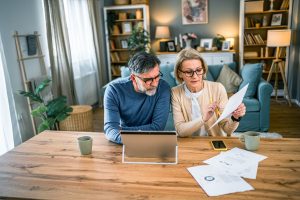Senior couple reviewing health insurance documents at home with a laptop and paperwork in the U.S.